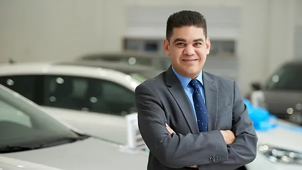 car deal link building authority confident man leaning against car arms folded