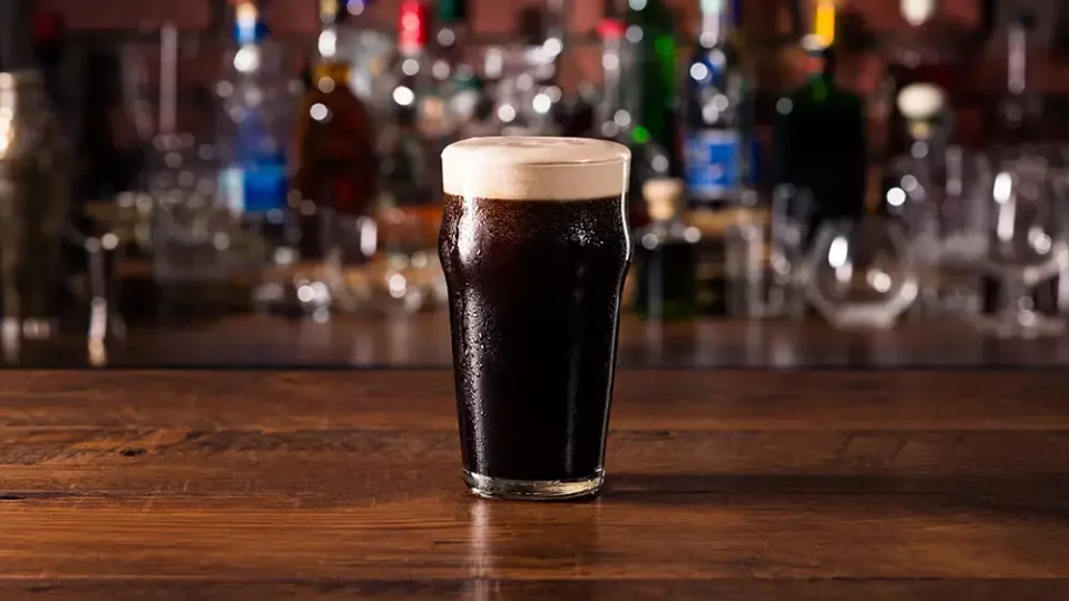 refreshing dark stout glass of guinness on wooden bar